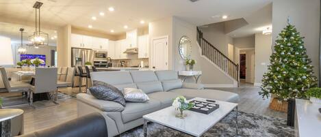 A modern living room with a gray sofa, a coffee table, and a Christmas tree.