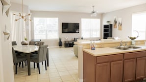 Una cocina moderna con comedor, una isla grande con fregadero y un televisor de pantalla plana montado en la pared.