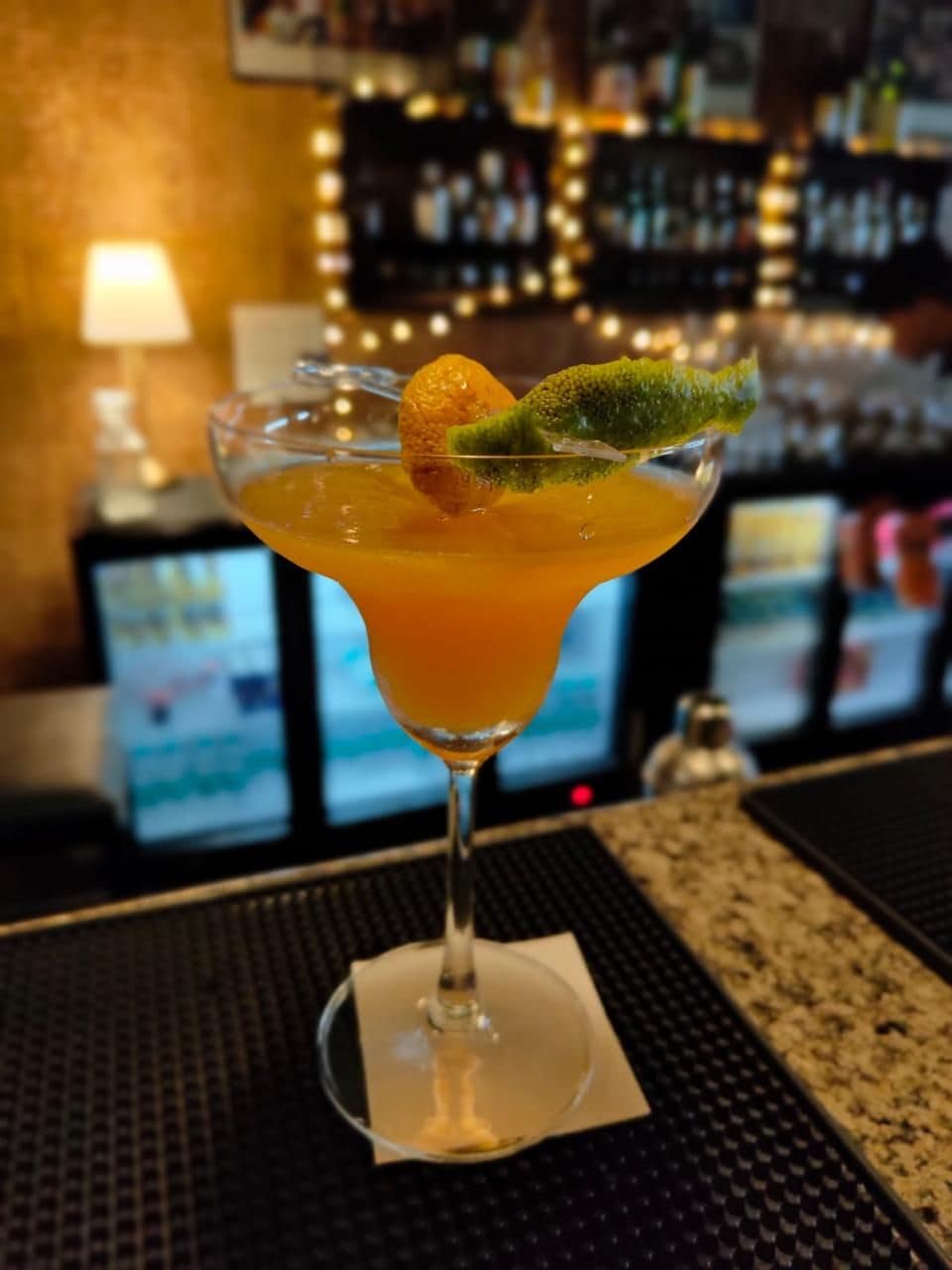 A cocktail with a lime garnish on a bar counter.