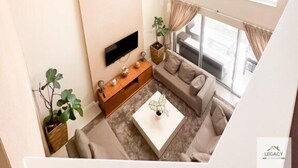 Un salón amplio con un gran ventanal, un televisor de pantalla plana, un sofá, una mesa de centro y una planta.