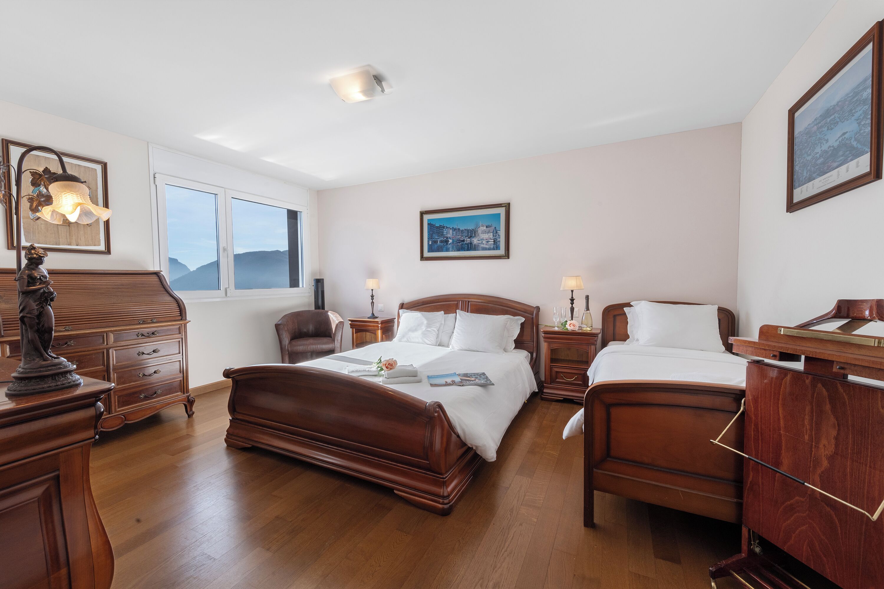 Une chambre spacieuse avec deux lits en bois, une commode, une chaise et une table de chevet.