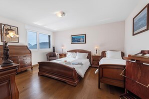 A spacious bedroom with two wooden beds, a dresser, a chair, and a nightstand.