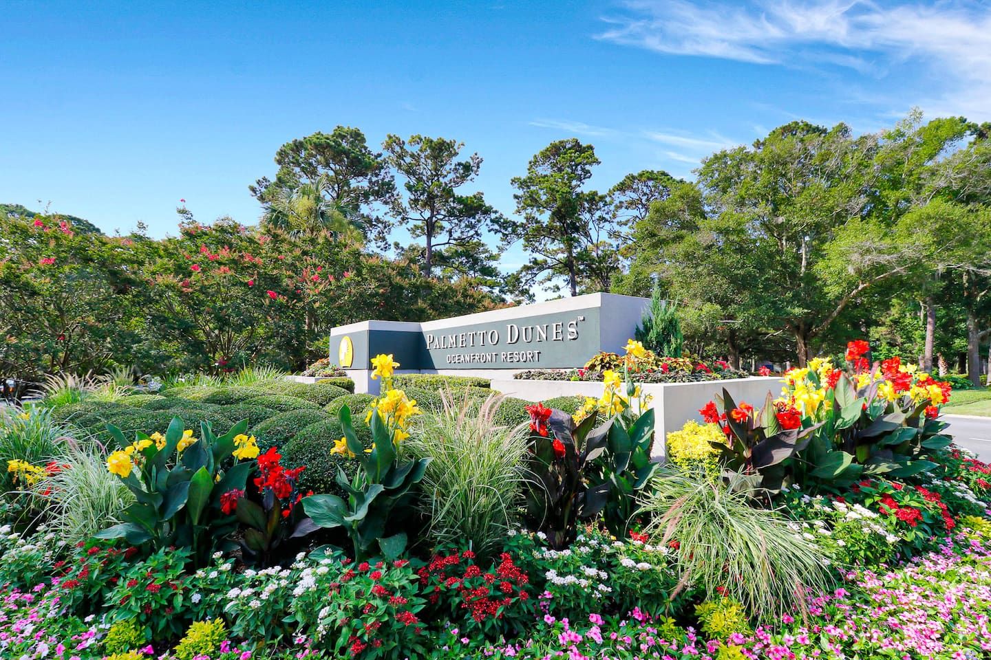 A sign for Palmetto Dunes Oceanfront Resort surrounded by a variety of colorful flowers and greenery.