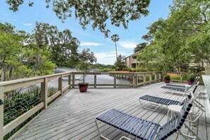 A wooden deck with lounge chairs and a potted plant, overlooking a body of water and a golf course. - Walk to Beach & Golf | 2 BR Palmetto Dunes Villa (Hilton Head Island)