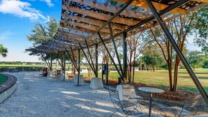 En utomhusplats med en pergola, sittplatser och en gångstig av grus.
