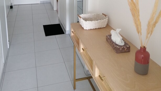A hallway with a wooden console table, a mirror, a framed picture, and a ceiling light fixture.