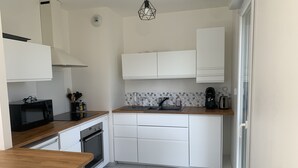 A compact kitchen with white cabinets, a microwave, a coffee maker, and a wooden countertop.