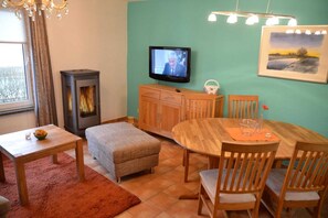 Un salon chaleureux avec une cheminée, un téléviseur, une table à manger et un tableau accroché au mur.