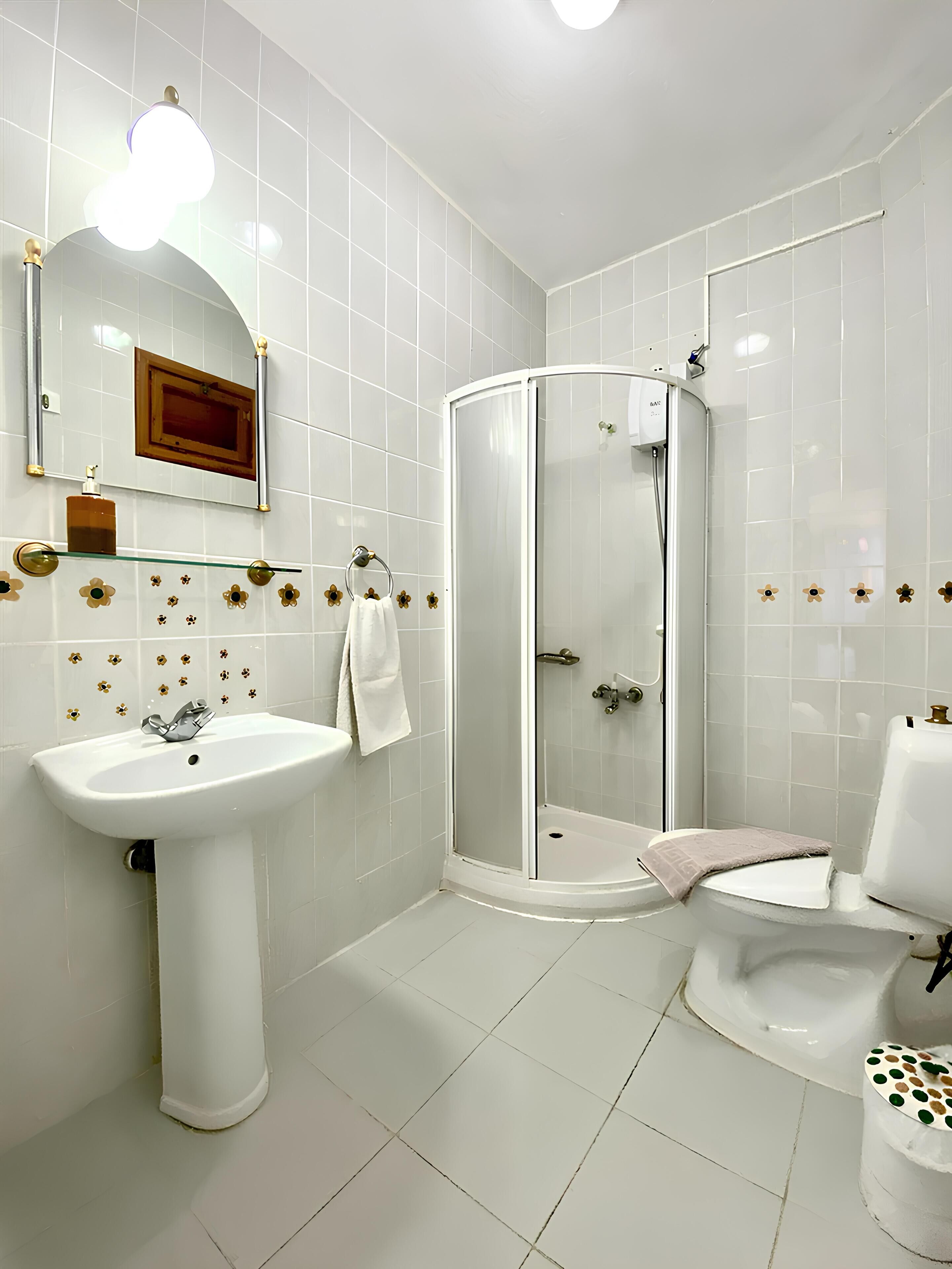 A bathroom with a white sink, a glass shower enclosure, and a toilet.