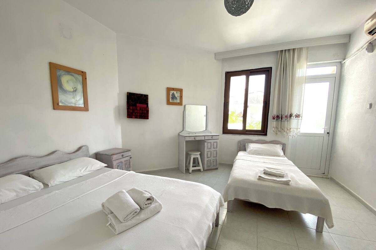A hotel room with two beds, a desk, a chair, and a window with curtains.