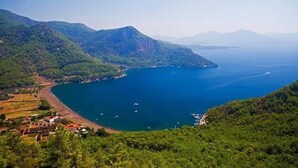 A coastal landscape with a beach, boats, and lush greenery. - Akdeniz Pansiyon (Koycegiz)