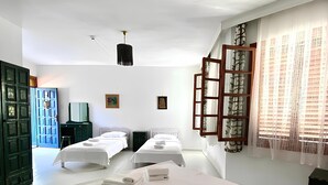 A hotel room with two beds, a large window with sheer curtains, a wooden wardrobe, and a ceiling light. - Akdeniz Pansiyon (Koycegiz)