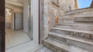 A stone staircase leading to a higher floor, a modern kitchen with a stainless steel refrigerator, and a glass door entrance. - 1159 Perla Bianca by Perle di Puglia (Ugento)