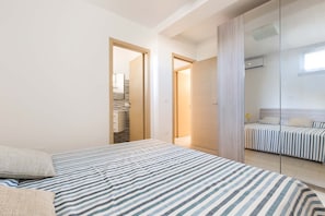 A bedroom with a bed, a mirror, and a door leading to a bathroom.