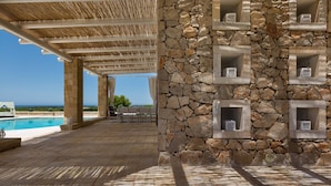 A covered outdoor area with a stone wall, a pool, and a view of the sea. - 1159 Perla Bianca by Perle di Puglia (Ugento)