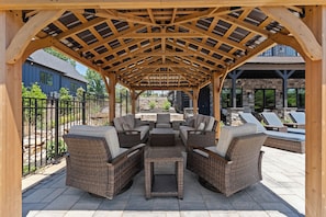 A covered outdoor seating area with wicker furniture and a pergola structure.