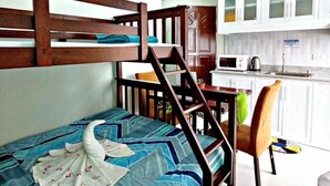 A bunk bed with a swan-shaped towel, a wooden desk, a chair, and a kitchen area with cabinets and a sink. - RM Grandview Residences (Baguio)