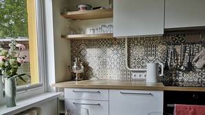 Une cuisine moderne avec des armoires blanches, un pare-feu décoré et un comptoir en bois. On peut voir deux verres de jus d’orange sur la table.
