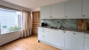 Eine Küche mit hellen Schränken, einer Spüle und einem Fenster mit Vorhängen.