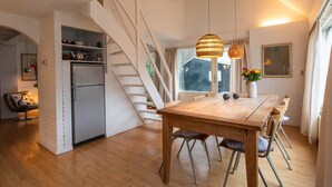 Eine moderne Küche mit integriertem Kühlschrank, einem Holzespeisesaal mit Stühlen, einer Treppe und einer Pendelleuchte.