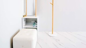 A minimalist room with a white ottoman, a white shelf with items, and a wooden floor lamp. - NP Pool Villa Hua Hin (Hua Hin)