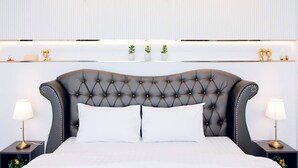 A hotel room with a tufted headboard, white bedding, and a sign reading "NP Pool Villa" on the wall. - NP Pool Villa Hua Hin (Hua Hin)