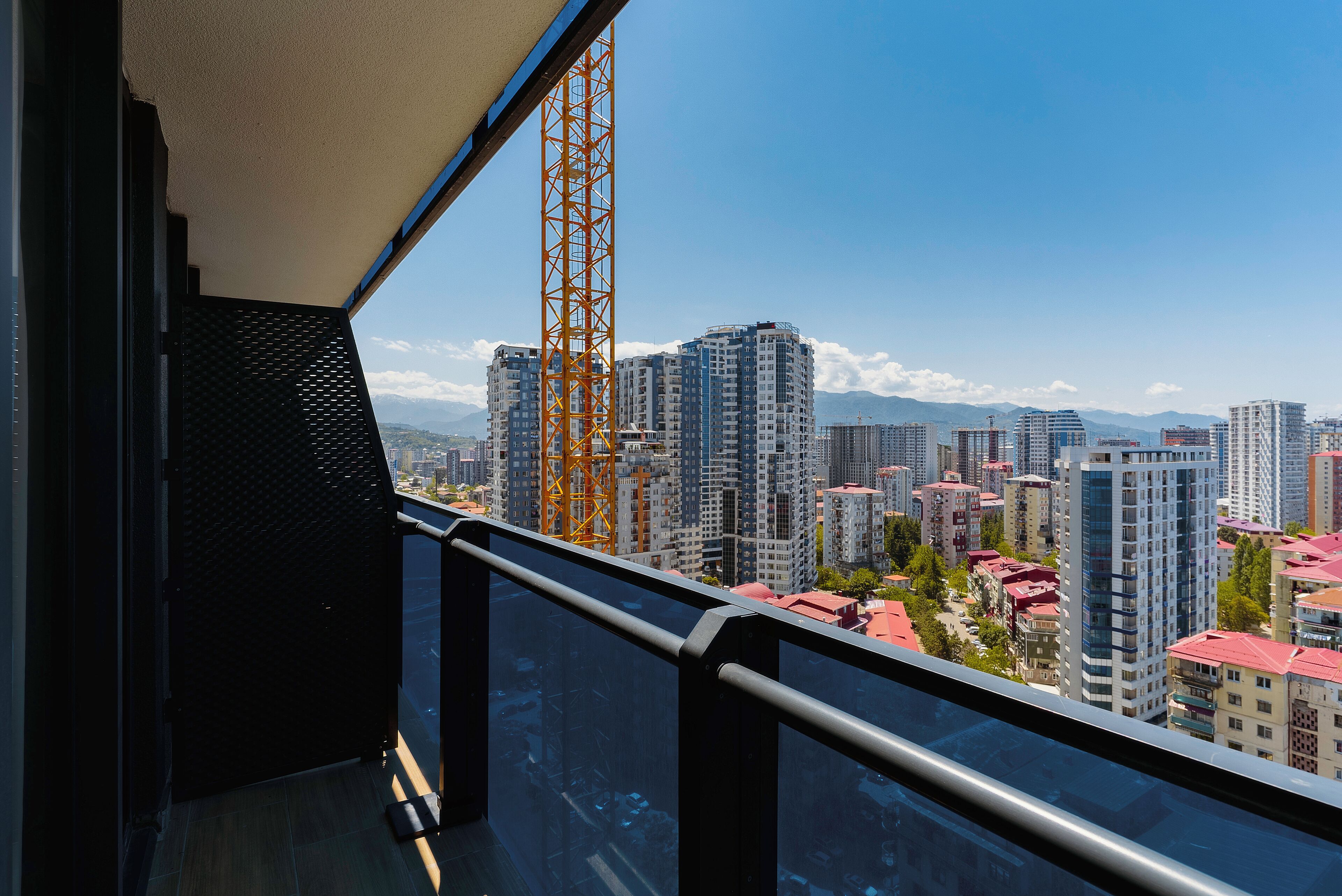 A high-rise building with a view of a cityscape, including several other tall buildings and a crane.