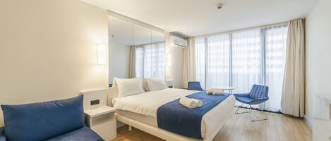 A hotel room with a bed, a blue sofa, a small table, and a chair.