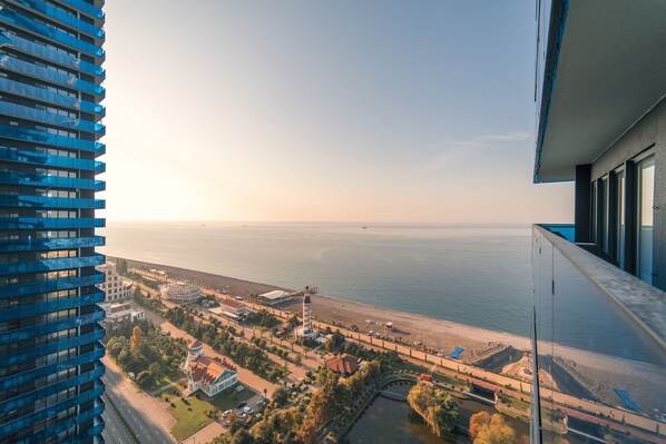A high-rise building with a view of a coastal area, including a beach and a body of water.