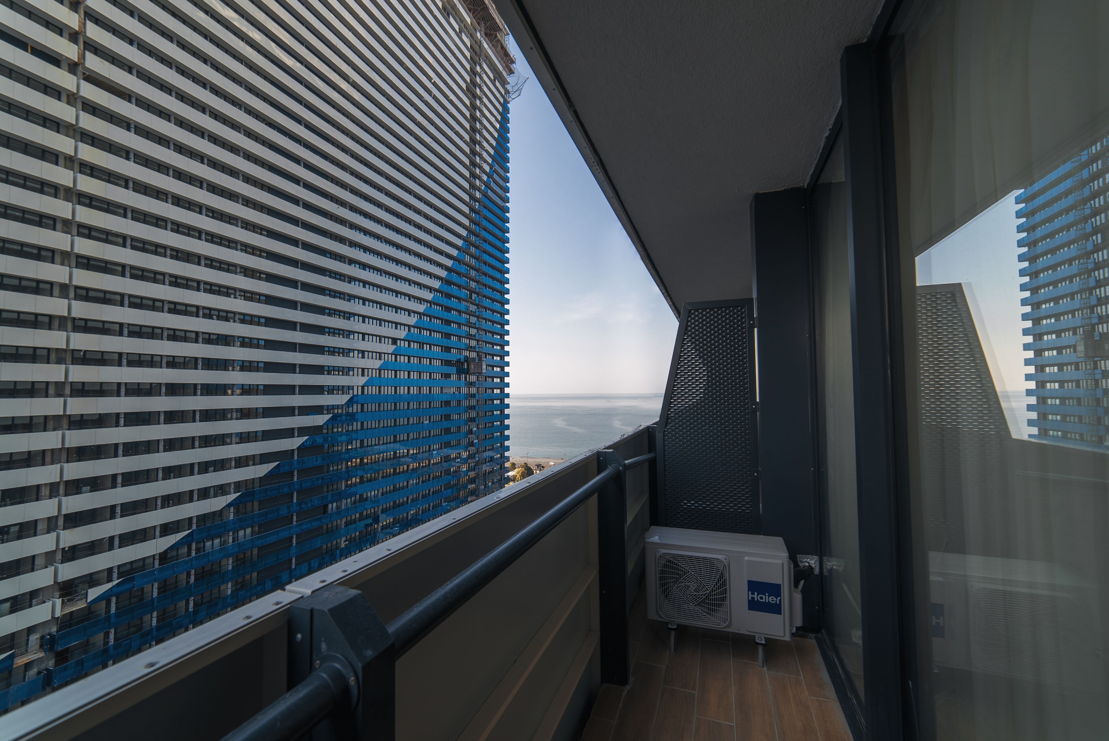 A balcony with a view of a modern building and the sea.