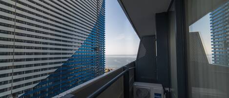 A balcony with a view of a modern building and the sea.