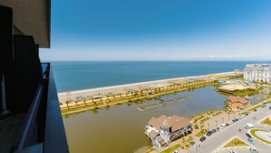 An aerial view of a coastal area with a marina, a beach, and buildings. - Grand City Real Estate (Batumi)