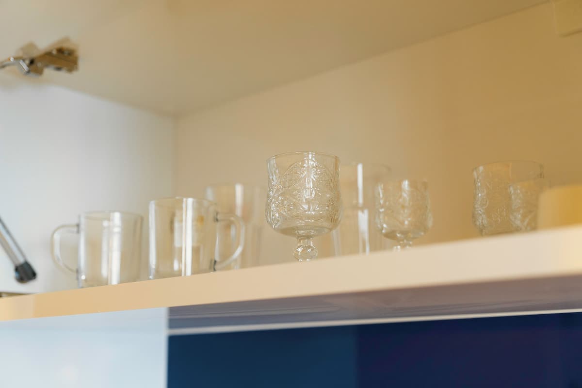 A shelf with various glassware, including a clear glass, a glass with a stem, and a glass with a handle.