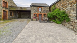Un patio con edificios de piedra, un sendero pavimentado y una pequeña zona de estar con mesa y sillas.