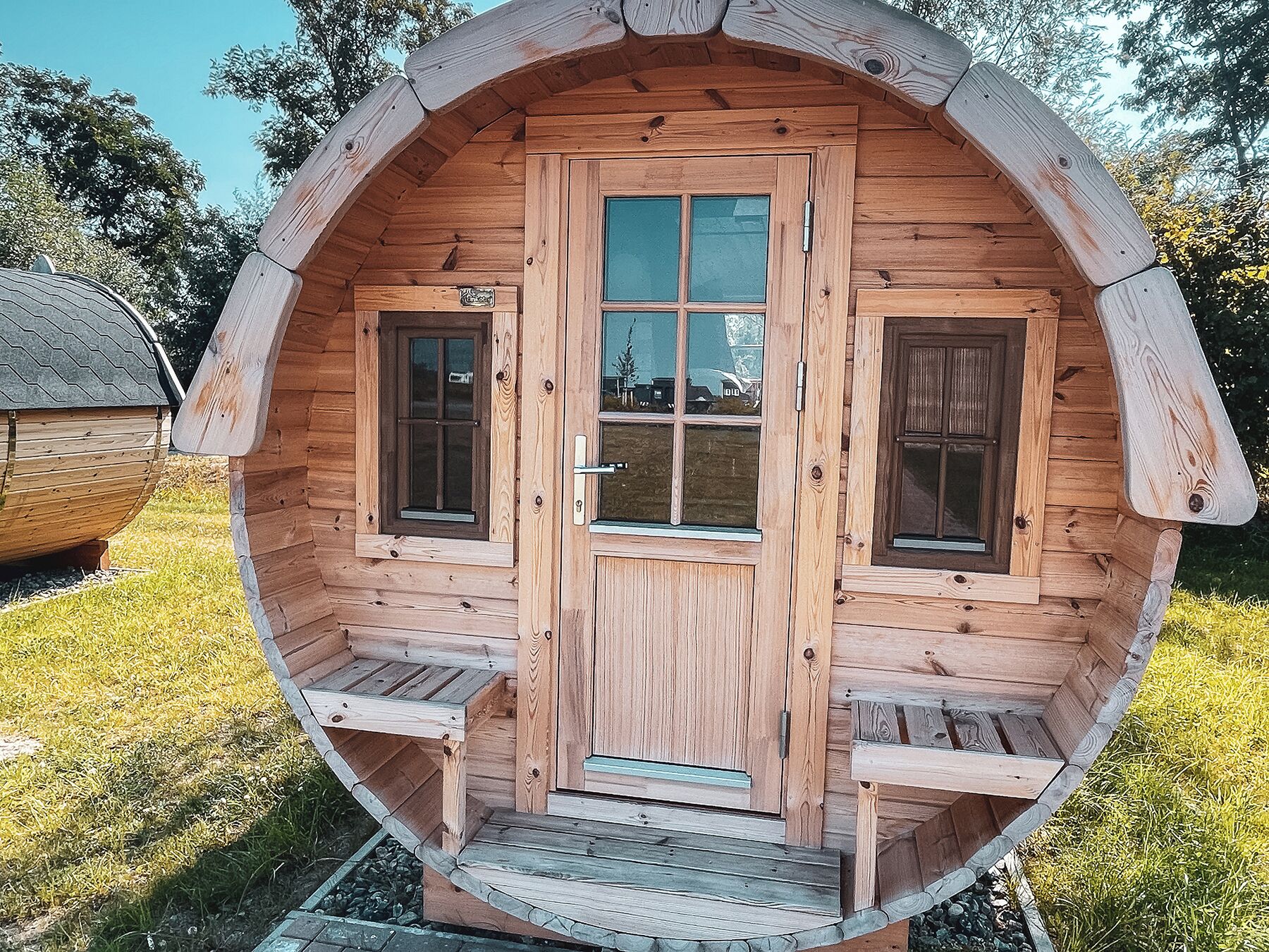 Una cabaña de madera con una puerta central, dos ventanas a cada lado y un pequeño porche.