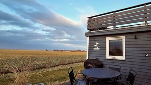 Una terraza con mesa y sillas, con vistas a un campo.