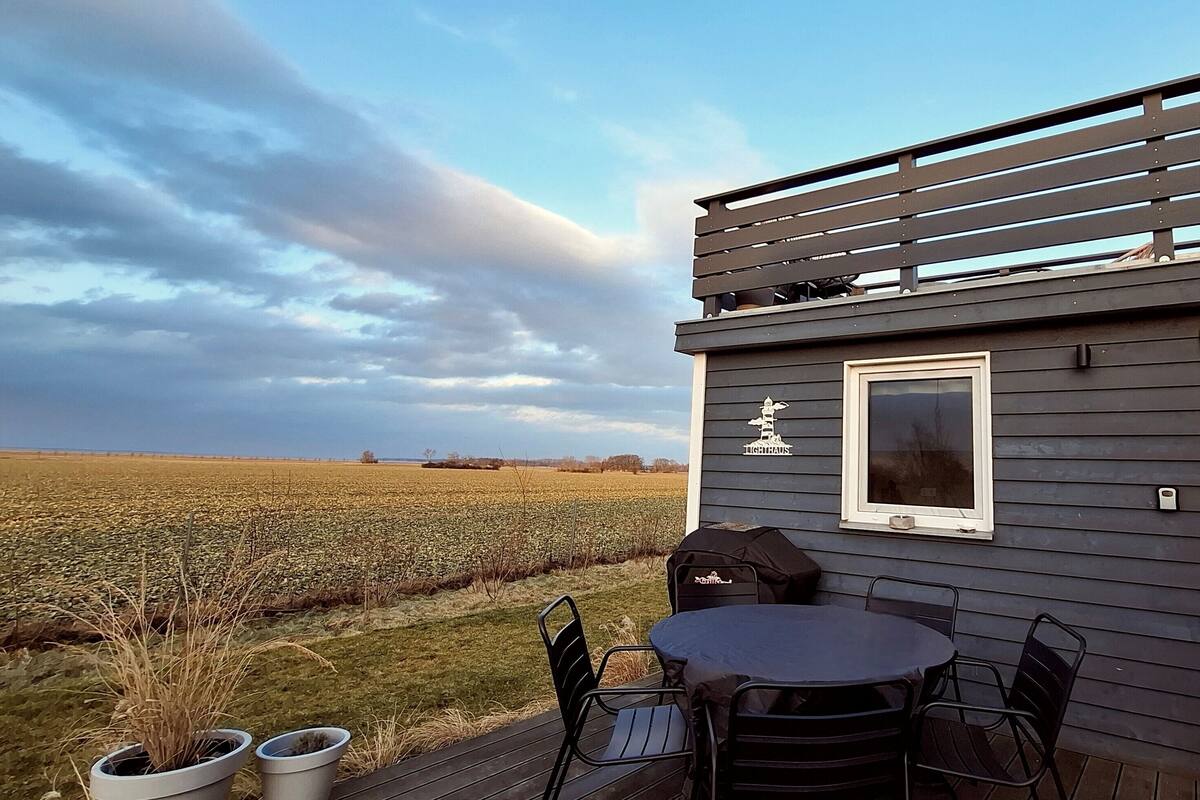 A deck with a table and chairs, overlooking a field.