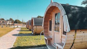 Una hilera de cabañas de madera con ventanas arqueadas y un sendero de ladrillo que las conduce.