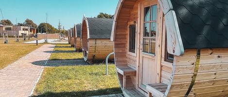 A row of wooden cabins with arched windows and a brick pathway leading to them.