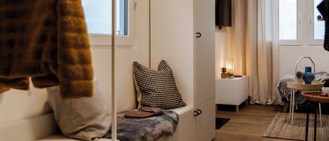 Una habitación moderna con sofá, televisión, una mesita con lámpara y ventana con cortinas.