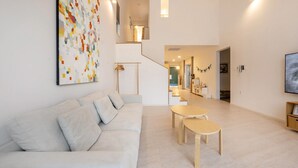 A modern living room with a sofa, a coffee table, and a staircase leading to a kitchen area.