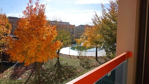 A balcony with a view of autumn trees and a circular water feature. - Gorgeous Caorle resort near the beach (Caorle (VE))