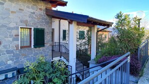 Ein Steinhaus mit Balkon und einer Treppe zu einer überdachten Veranda.