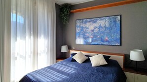 Ein Hotelzimmer mit einem großen Bett, zwei Nachttischlampen, einem Bild an der Wand und transparenten Vorhängen.
