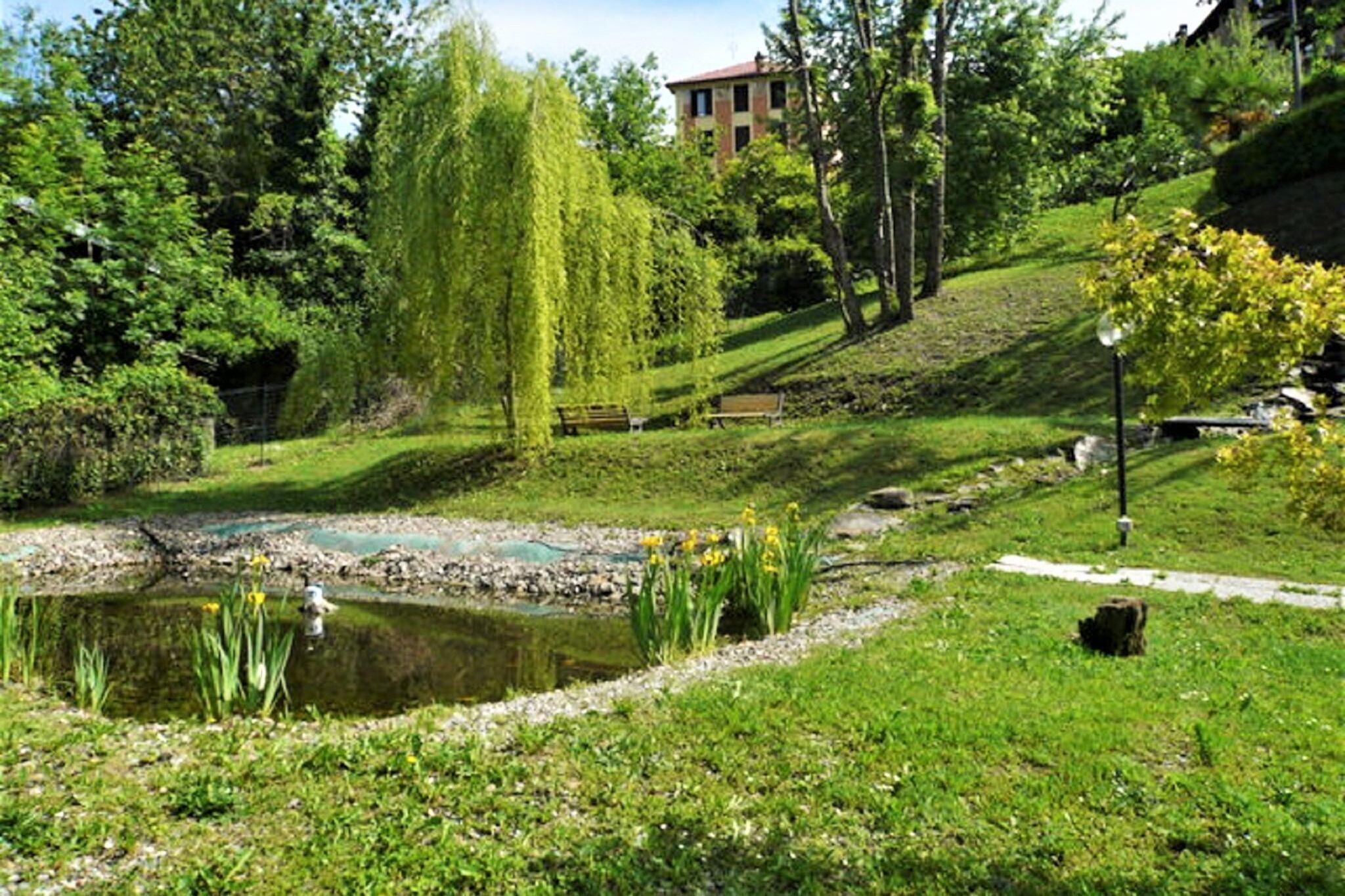 Ein friedlicher Park mit Teich, Bänken und einer Weide.