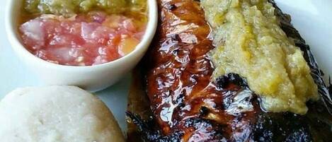Une assiette de viande grillée, accompagnée d’un accompagnement de riz et d’un bol de salsa.