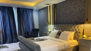 Ein Schlafzimmer mit einem großen Bett, einem gesteppten Kopfteil, einem Nachttisch und einem Sessel.
