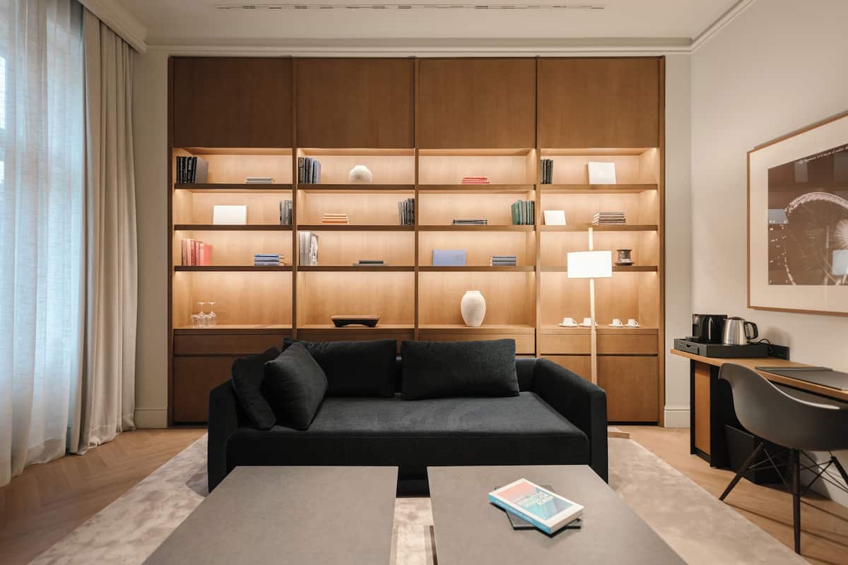 A modern living room with a dark grey sofa, a coffee table, and a bookshelf filled with books and decorative items.