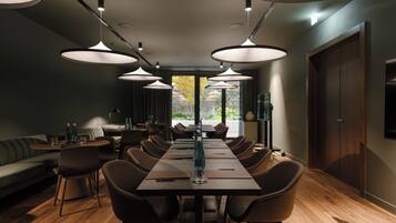 A modern dining area with a long table, multiple chairs, and pendant lighting.