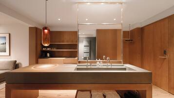 A modern bathroom with a large mirror, wooden cabinets, a built-in sink, and a towel rack.